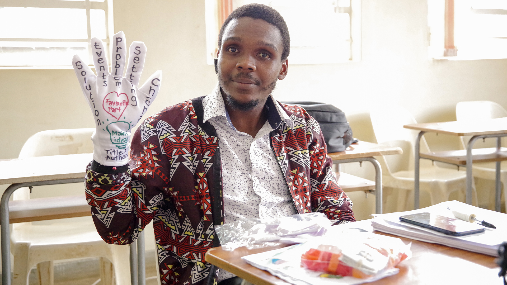 One of the participants in the foundation literacy course training. He has a glove on one hand with words written on the palm and fingers of the glove.