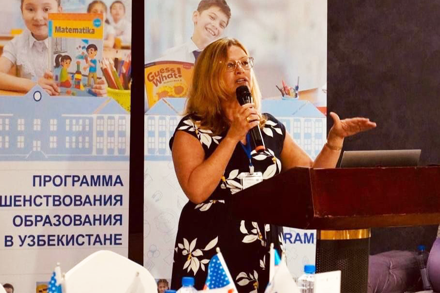 Flavia Ramos-Mattoussi at a podium presenting in Uzbekistan