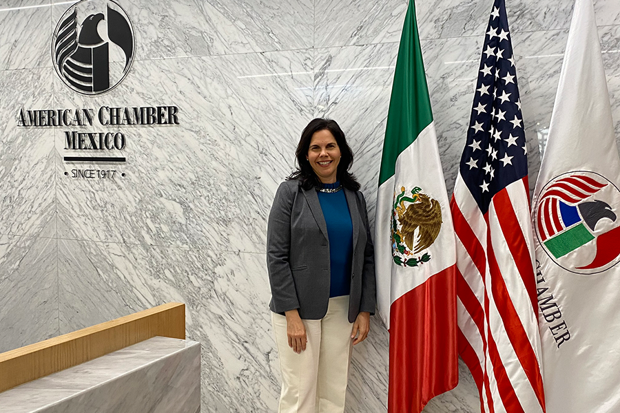 Vilma Fuentes posing in front of three flags inside a building in Mexico