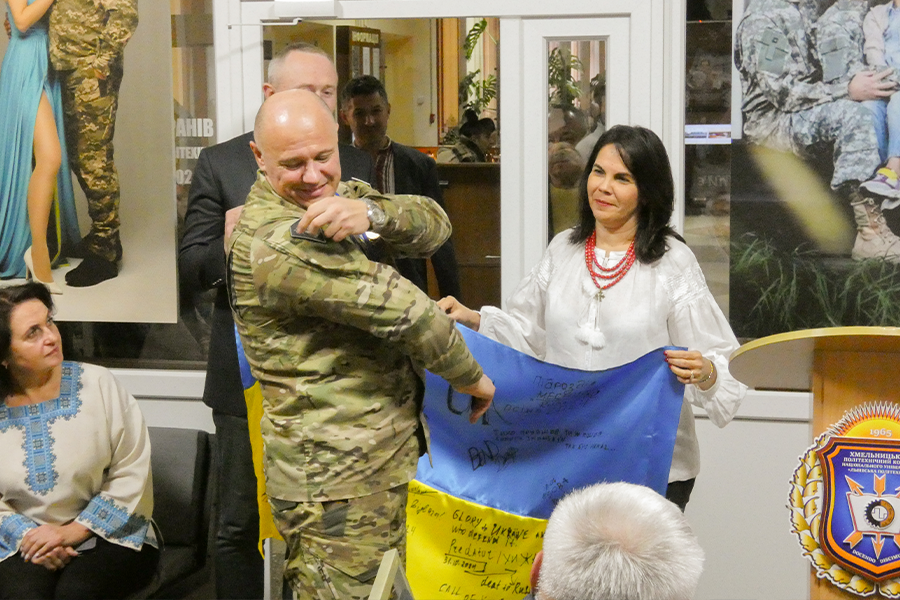Vilma Fuentes holding the Ukrainian flag with a group of Ukrainian military personnel