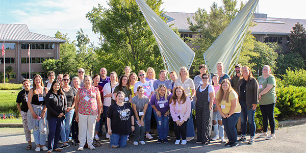 "Group photo of teachers in front of a sculpture at the FSU Aero-Propulsion, Mechatronics, and Energy building."