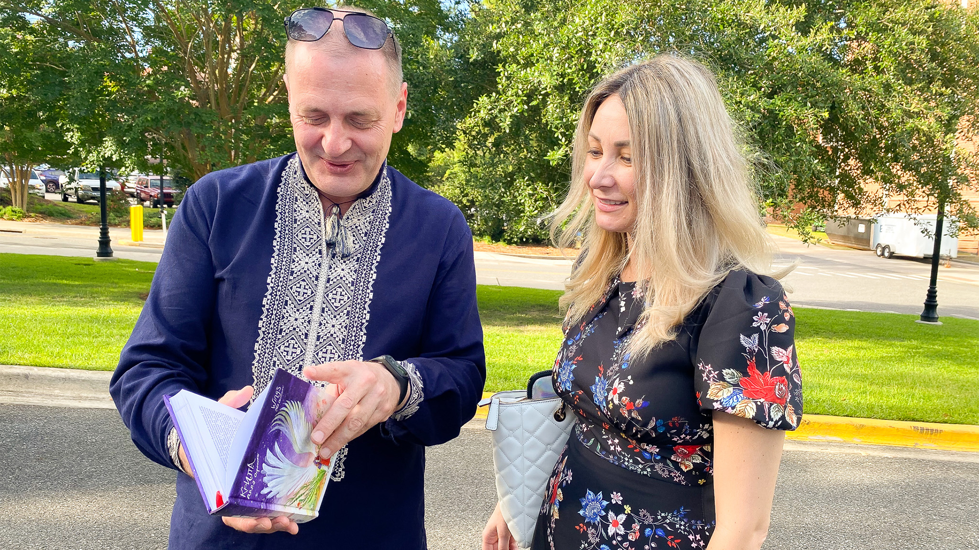 "Dr. Andrii Roskalda outdoors looking at a book with Dr. Anna Romanova"