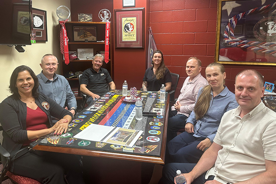 "Ukrainian visitors pose round a table during a meeting at the FSU student veterans center"