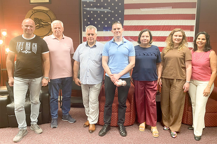 "Ukrainian visitors pose in front of a large USA flag during a meeting at the FSU student veterans center"