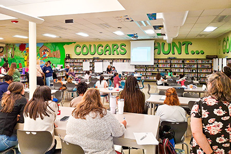 "Classroom full of people looking at a presentation at the front of the room"