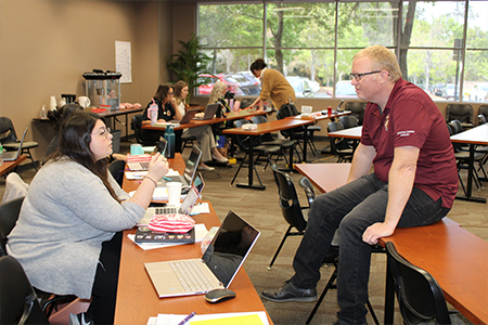 "JiM Reynolds sitting on a table in a discussion during a workshop."