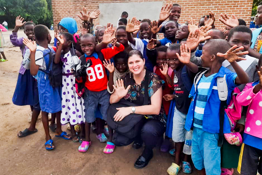 "Dr. Adrienne Barnes-Story posing with a large group of school children in Africa"