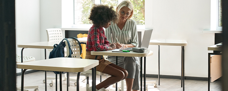 "A woman and a child are sitting at a desk working on schoolwork."