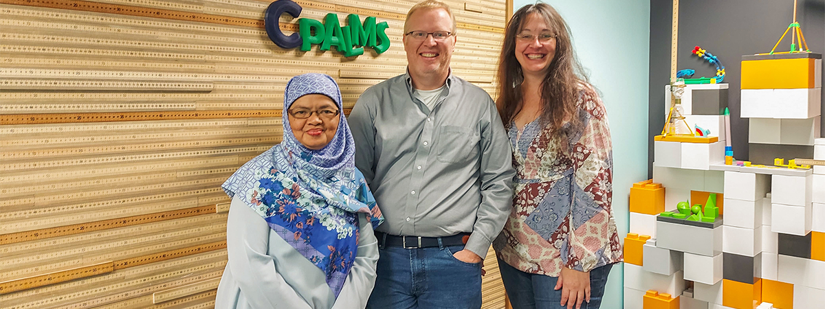 "Dr. Djulia with LSI faculty members Carrie Meyers and Jim Reynolds in front of a CPALMS wall sign."