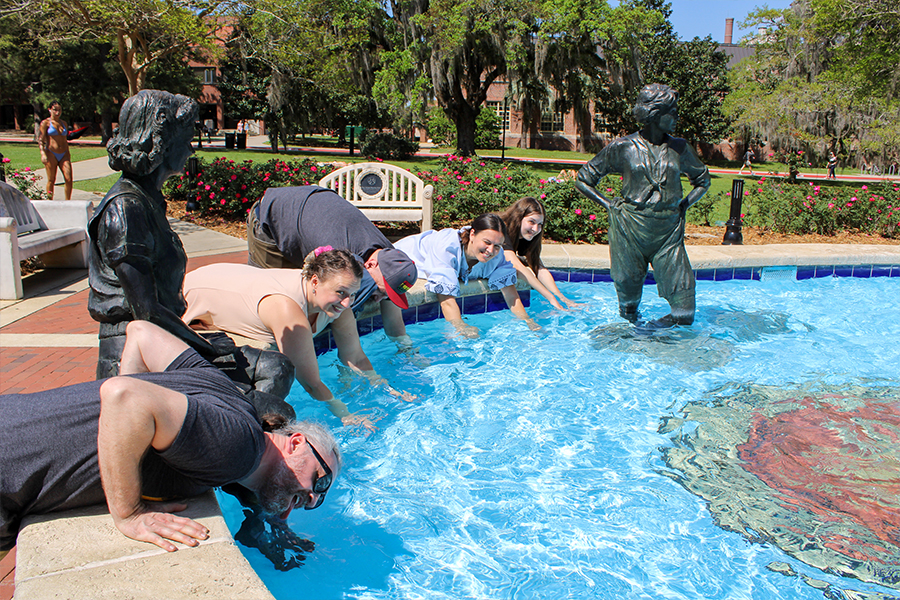 DakhaBrakha walking outdoors on the FSU campus leaning into the water at the Legacy Fountain.