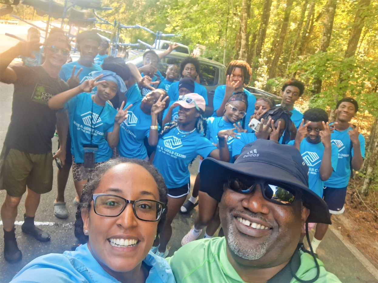 Selfie group photo of Dr. Tazaz and Boys & Girls Club campers posing in the woods.