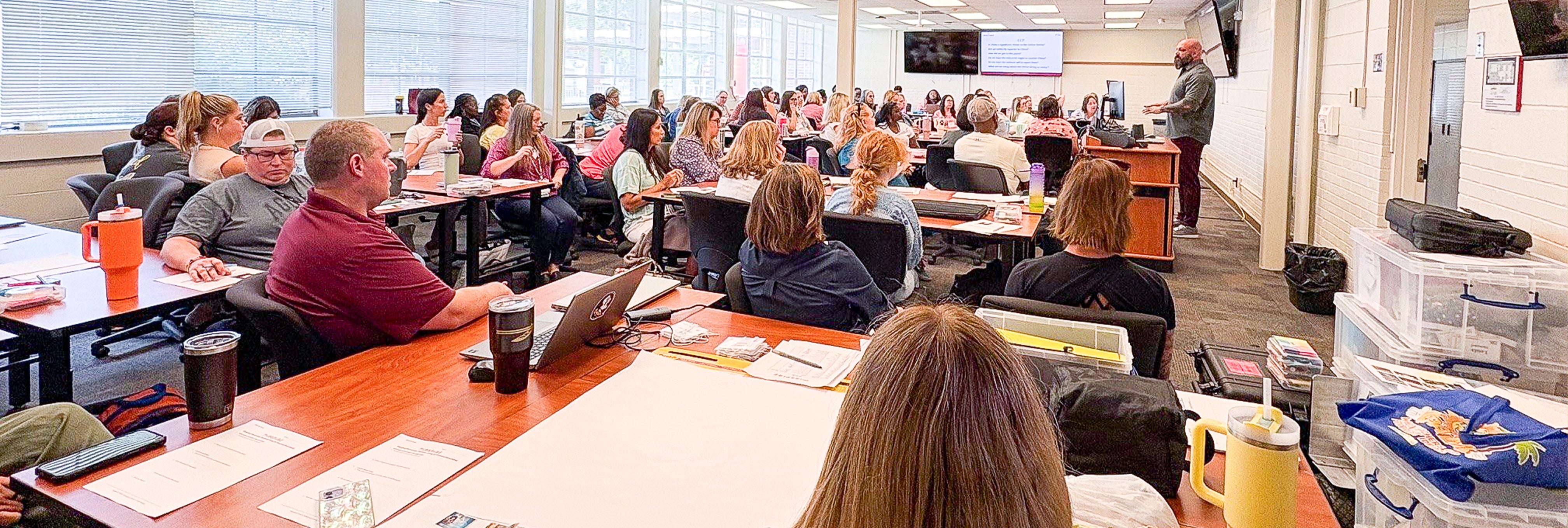Drew Allen addressing a group of educators from a podium in a classroom.