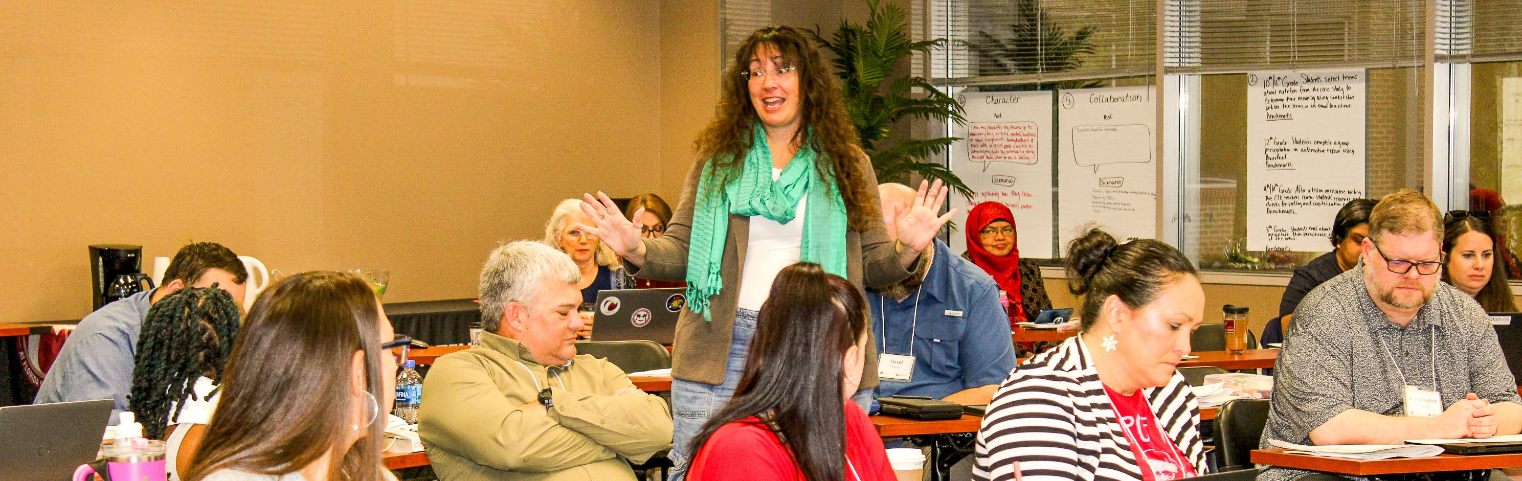 Carrie Meyers standing in the middle of a room surrounded by workshop participants listening to her presentation.