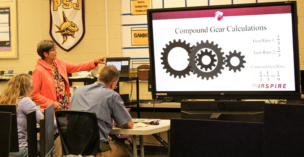 Instructor at an InSPIRE professional development session standing in front of a large screen.