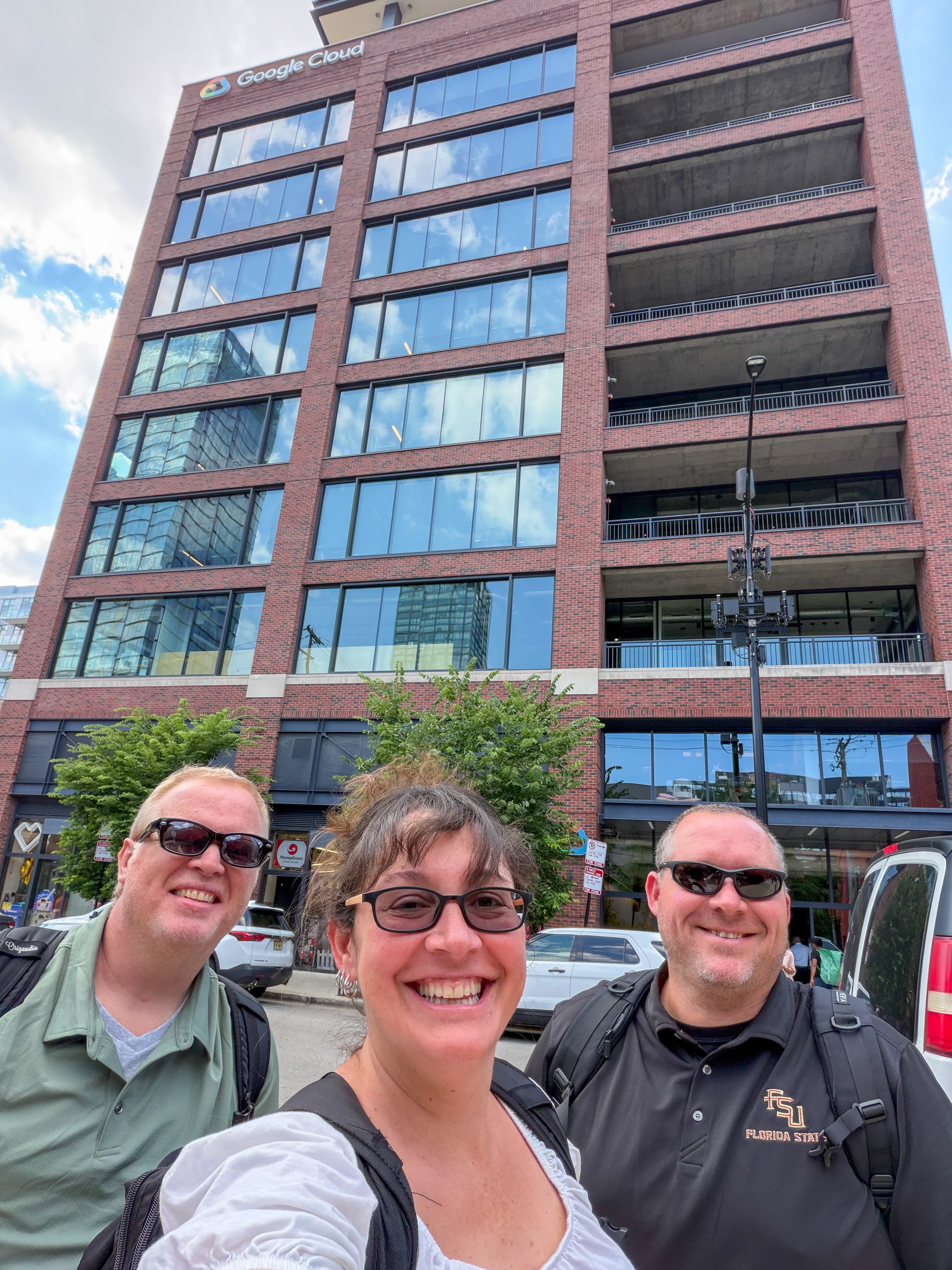 Carrie Meyers, Jim Reynolds and Robert Hanna pose for a photo outdoors in front of the  Google Cloud headquarters. building
