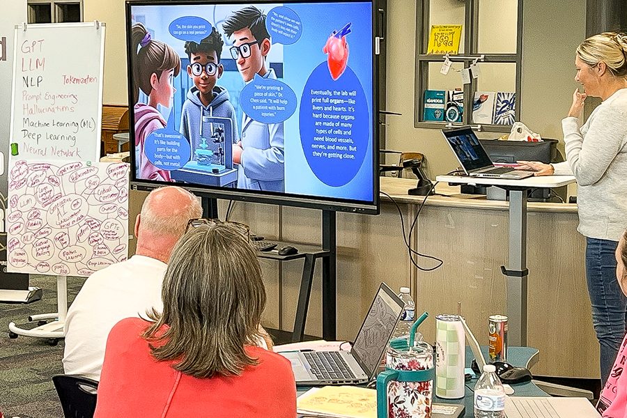 A person presents on AI in education at a digital workstation with a large screen displaying human figures.