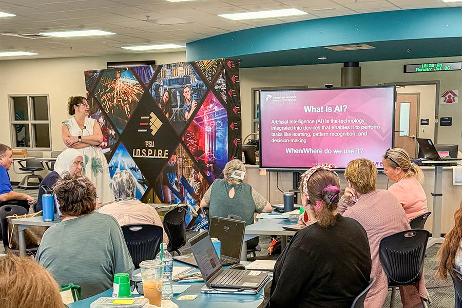 LSI's Carrie Meyers conducting an AI in education session standing next to a flat screen TV.