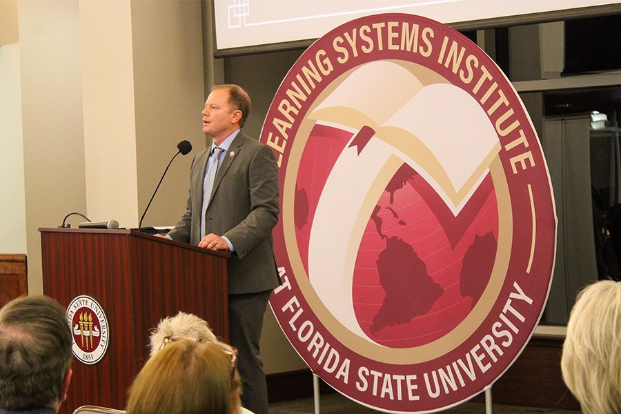 Robert C. Schoen presenting in front of a large backdrop of the LSI logo.