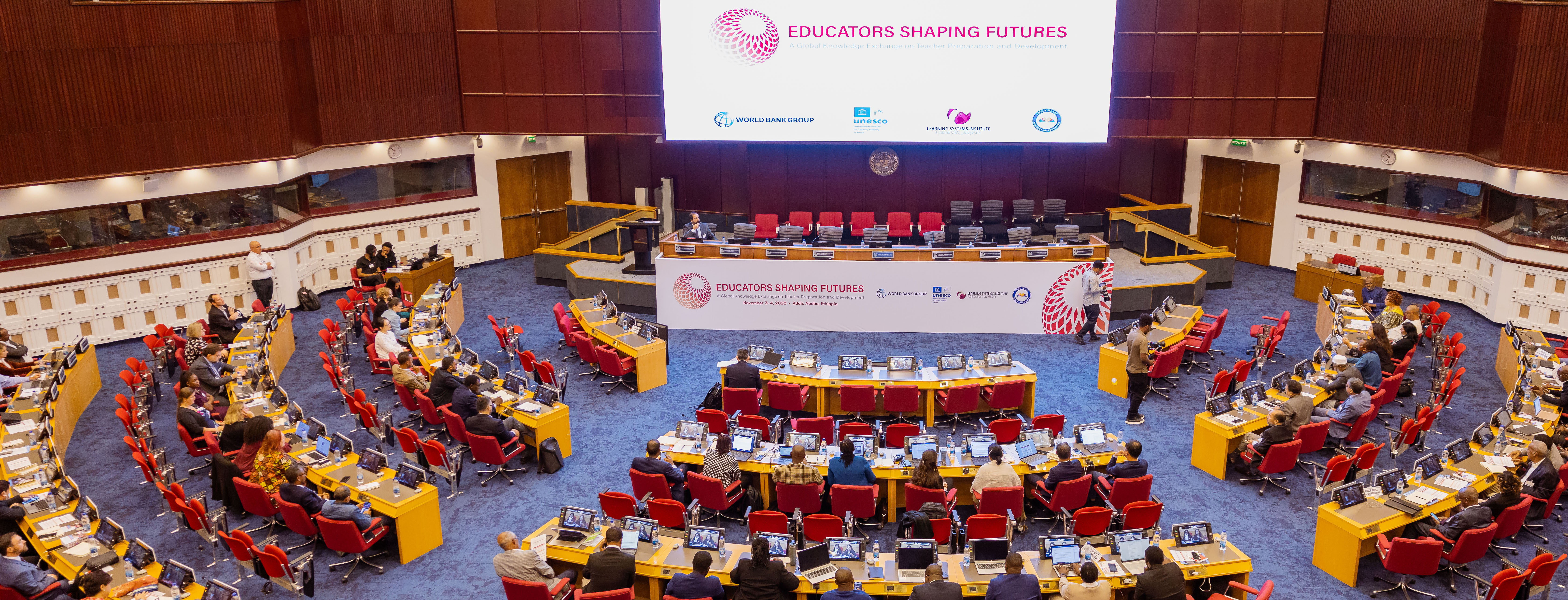 Wide photo of a large conference room with a giant projection screen in front.