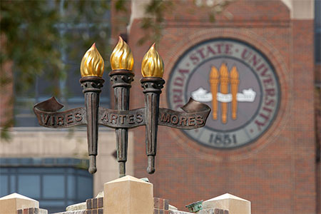 FSU campus building with the university seal in stained glass and a fountain with the three torches.