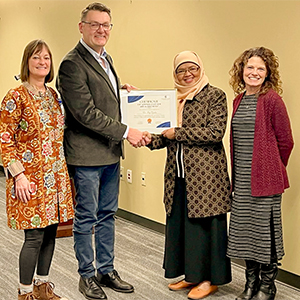 Dr. Ely Djulia Katmadihardja receiving a certificate from three representatives from Columbus State University.