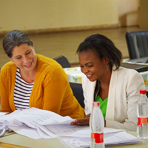 "Two people sitting, looking at materials and smiling"