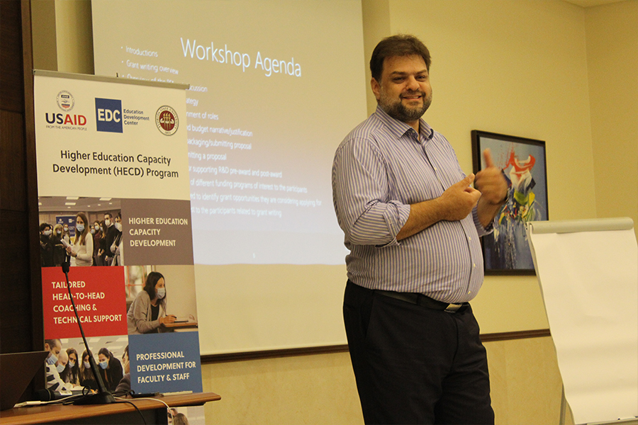 "Rabieh Razzouk presenting in front of a projection screen"