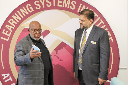 "President of the United Nations General Assembly, Mr. Dennis Francis presenting LSI Director Rabieh Razzouk with a copy of the UN Charter in front of a large LSI globe logo. "