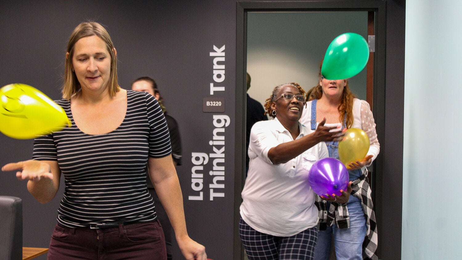 Two women bouncing balloons off their hands while walking.