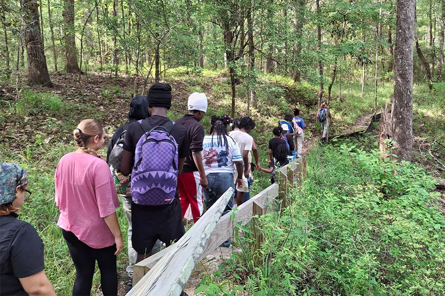 Students hiking a trail in a forest.