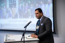 A presenter at a podium next to a projection screen