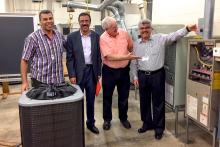 A small group in a classroom posing next to HVAC equipment