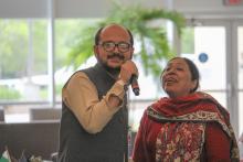 Two people standing and one is holding a microphone