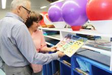 A man and a woman in a classroom looking at a child's learning activity