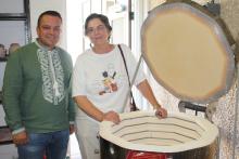 Two people standing next to a kiln 