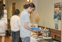 A man reading some of the supplied material at a display table. 