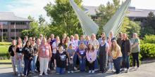 Group photo of teachers in front of a sculpture at the FSU Aero-Propulsion, Mechatronics, and Energy building. 