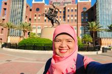 Dr. Ely Djulia Katmadihardja takes a photo in front of the Unconquered Statue on the campus of FSU in front of the football stadium.