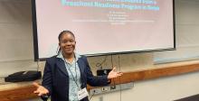 Brenda Wawire posing in front of a projection screen at a conference.