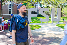 DakhaBrakha's Marko Halanevych walking past a large FSU installation of campus. 
