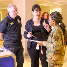 Jim Reynolds and Carrie Meyers in discussion with a women in military camos. 