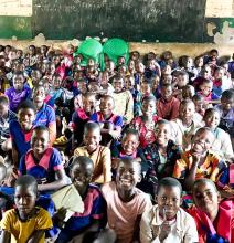 Classroom of students in Malawi sitting on the floor.