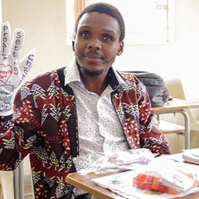 One of the participants in the foundation literacy course training. He has a glove on one hand with words written on the palm and fingers of the glove.