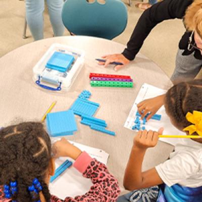 Teacher working with two you students at a table.