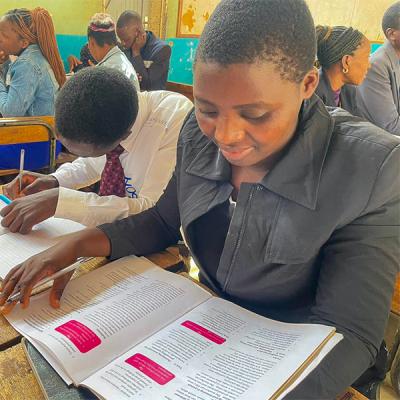 Woman reading a text book at a desk.