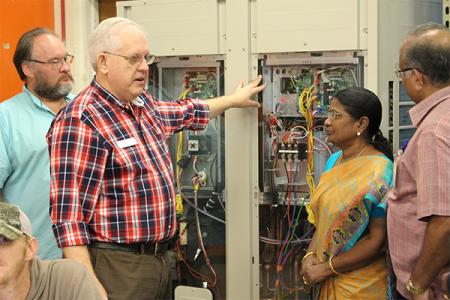 Man pointing at an electrical panel during a CCAP visit from India.  