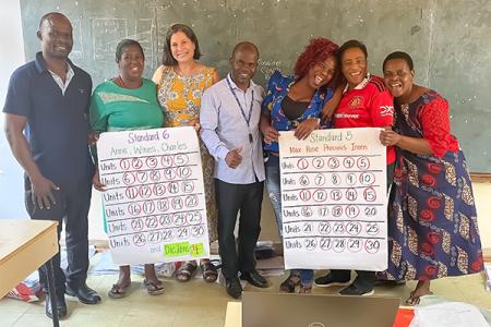 Dr. Jennie Robinette posing with educators in Malawi holding large pieces of cardboard with goals that have all been completed and checked off. 