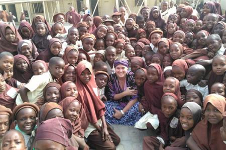 Dr. Adrienne Barnes-Story surrounded by a large group of children posing for a photo in Nigeria.