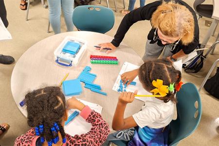 An instructor working at a small table with two children on CGI.