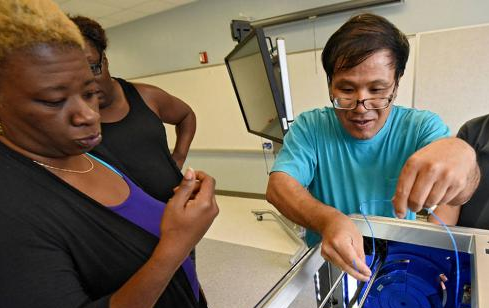 "Emma Pugh, at left, a mathematics coach at Westview K-8 School, and Ming Ziang, center, who teachers algebra at Frank H. Peterson Academies of Technology, learn how teachers can use 3-D printer in STEM classes."